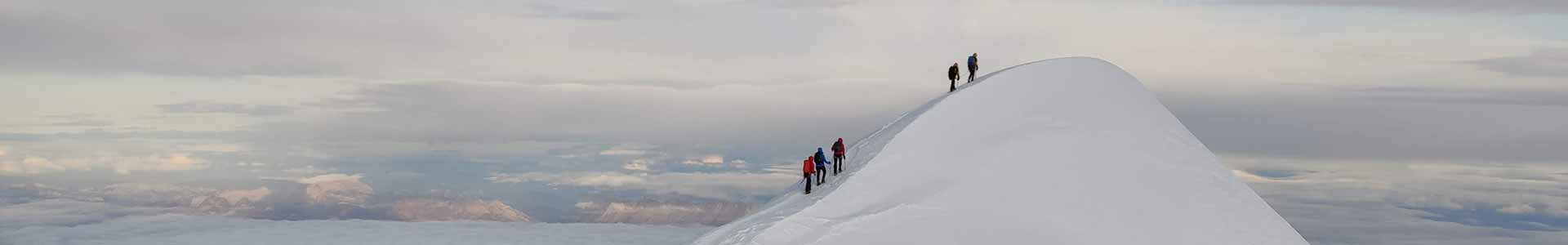 5 alpinistas llegando a la parte alta nevada de una montaña