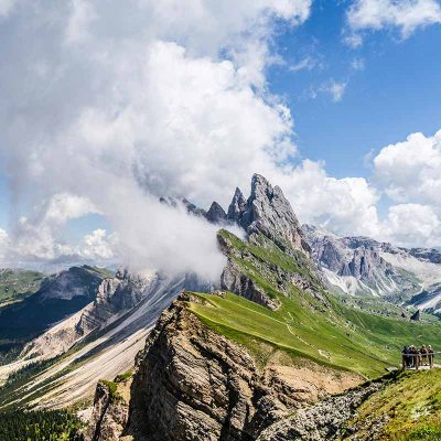 Picos de montañas con laderas con hierba y nubes en las cimas - Retiro de final de verano