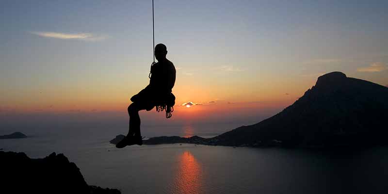 Escalador colgado de una cuerda sobre una bahía del mar - Gestión emocional - Terapia Mindfulness