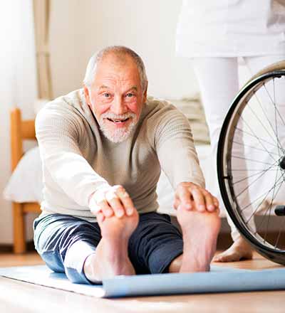 Persona mayor haciendo estiramientos en una esterilla - Tratamientos de fisioterapia - Fisioterapia traumatológica